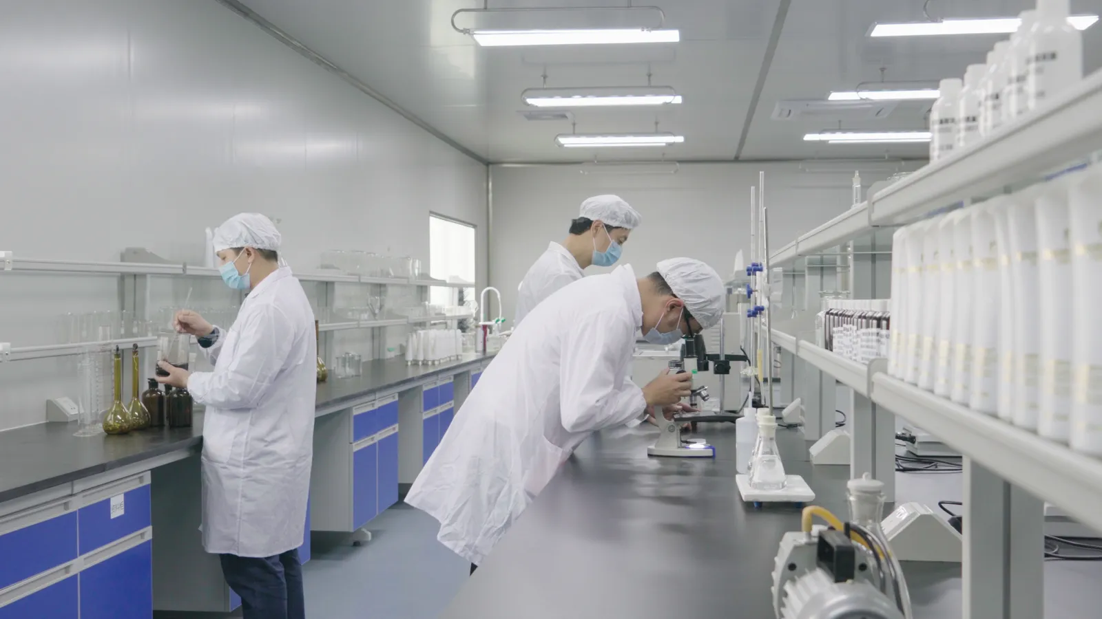 Three members of the in-house laboratory team at work at a lab bench with a microscope.